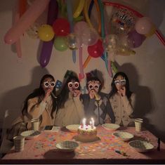 three girls wearing party glasses and holding up their faces in front of a birthday cake