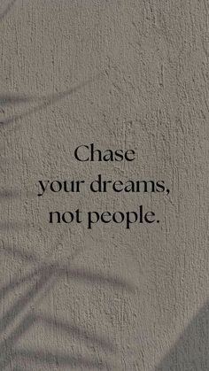 the words chase your dreams, not people are written in black on a gray wall