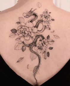 a woman's back tattoo with flowers and snakes