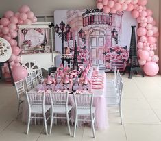 a table set up for a party with pink and white balloons on the wall behind it