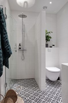 a white bathroom with black and white floor tiles on the shower, toilet and sink