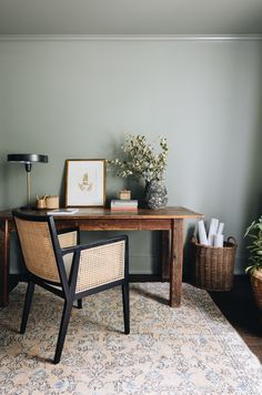 a desk with a chair, lamp and pictures on it