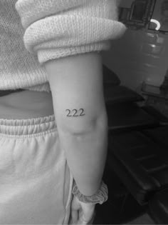 a woman's arm with the number 22 tattoo on her left side, while she is wearing white sweatpants