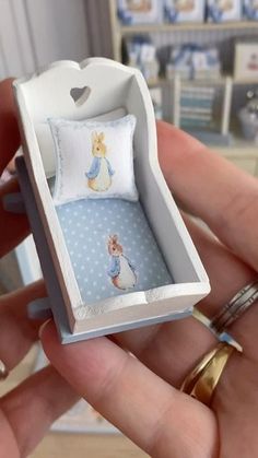 someone is holding a miniature dollhouse bed in a box that has been made into a pillow