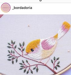 a bird sitting on top of a tree branch in front of a cross stitch pattern