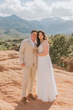 a bride and groom standing on top of a mountain