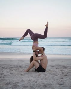 a man and woman are doing acrobatic tricks on the beach at sunset