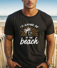 Escape to your happy place with our "I'd Rather Be at the Beach" tee. Whether you're stuck in the city or daydreaming at your desk, let this shirt transport you to sandy shores and salty breezes. Wear it as a reminder of the tranquillity and freedom found by the sea, and keep the beach vibes alive wherever you go. Size guide                             SMLXL2XL3XL4XL5XL A) Length (cm)71.173.776.278.781.383.88689 B) Half Chest (cm)45.750.855.9616671.17681                             SMLXL2XL3XL 4XL   5XL A) Length (cm)71.173.776.278.781.383.88689 B) Half Chest (cm)45.750.855.9616671.17681 Care instructions WashMachine wash warm (max 40C or 105F), wash garment inside out with similar colours Tumble DryLow BleachOnly non-chlorine Dry CleanDo not dry clean IronDo not iron 100% cotton Gildan 50 Black Letter Print T-shirt For Beach Season, Black Text Print T-shirt For Vacation, Beach Tee, Sandy Shores, Beach Vibes, Beach Vibe, By The Sea, Happy Place, At The Beach