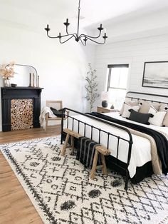 a white and black bedroom with a chandelier hanging from the ceiling, rug on the floor