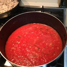 a pot filled with red sauce sitting on top of a stove next to an oven