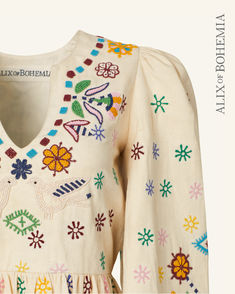 Detailed view of hand-beading and hand embroidery. V-neck Dress With Intricate Multicolor Embroidery, Traditional V-neck Embroidered Dress, Folk Style Embroidered Dress With Geometric Patterns And V-neck, Embroidered V-neck Dress, Multicolor V-neck Dress With Floral Embroidery, Multicolor V-neck Embroidered Dress With Floral Details, Traditional V-neck Floral Embroidered Dress, Spring Traditional Embroidered V-neck Dress, Traditional Spring Embroidered Dress With V-neck