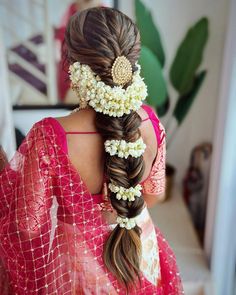 a woman with long hair and flowers in her hair is wearing a red sari