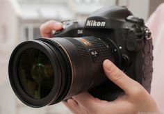 a person holding a camera in their hand with the lens up to their face and hands