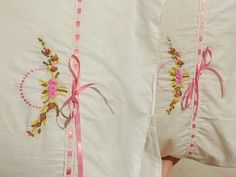 two white pillows with pink ribbons and flowers on them