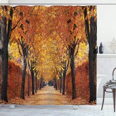 a shower curtain with an image of trees and leaves in fall colors on the ground