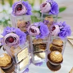 four clear boxes filled with different types of chocolates and flowers on top of a table