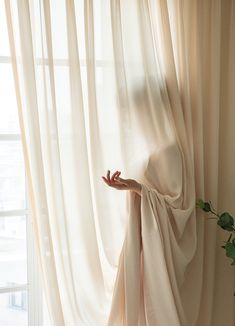 a person's hand is reaching out from behind the curtain to touch the window