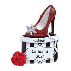 a red shoe sitting on top of a black and white box next to a rose