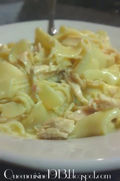 a white plate topped with pasta covered in chicken and cheese sauce on top of a table