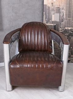 a brown leather chair sitting in front of a wall with a cityscape behind it