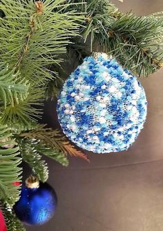 a blue and white ornament hanging from a christmas tree