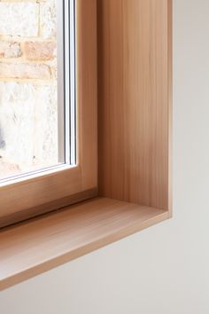 a cat sitting on the ledge of a window sill next to a brick wall