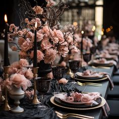 the table is set with black and gold place settings, pink flowers in vases