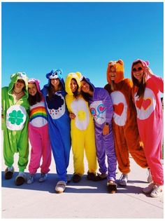 a group of people standing next to each other in animal onesuits on the beach