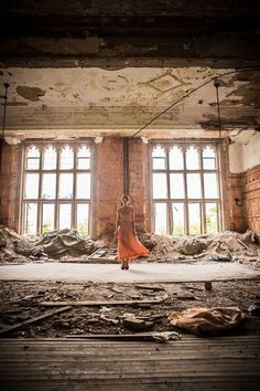 a woman in an orange dress walking through a room with lots of debris on the floor