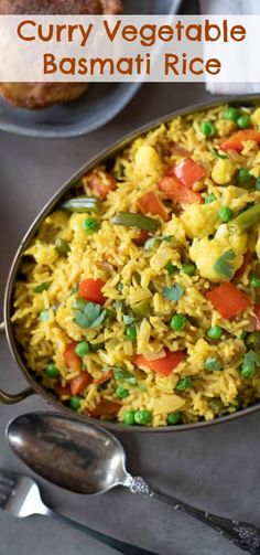 a pan filled with rice and vegetables on top of a table next to silverware