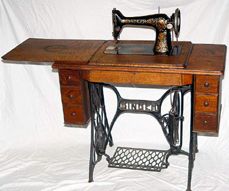 an old sewing machine sitting on top of a wooden table with two drawers underneath it