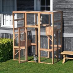 a wooden structure with two cages on top of it in the grass next to a bench