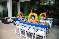 a table set up for an outdoor party with balloons and decorations on the tables,