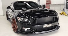 the front end of a black mustang in a garage