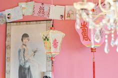 a chandelier hanging from a pink wall with pictures on it