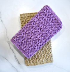 two crocheted cloths sitting on top of a white counter next to each other