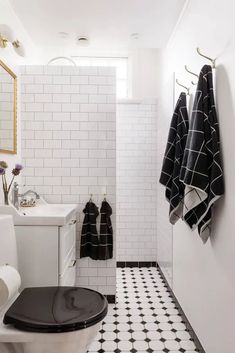 a bathroom with black and white tile flooring and walls, along with two hanging towels