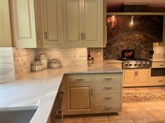 a kitchen with white cabinets and marble counter tops