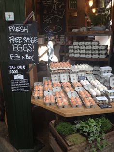 an outdoor market with eggs for sale on the table and in front of it is a sign that says fresh free range eggs