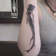 a woman with a black and white tattoo on her arm is holding onto the arm