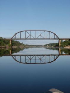 a large bridge over a body of water with a boat in the foreground and trees on either side