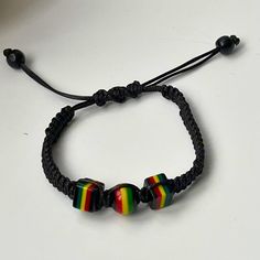 Feel the island vibes with this adjustable braided cord and reggae rasta beads bracelet for him or/and for her! This stylish bracelet is made with a high-quality cord that was hand braided and can be adjusted to fit any wrist size. The bracelet is adorned with colourful rasta beads, inspired by the Rastafarian movement and reggae music. Here are some of the features of this bracelet: *Adjustable braided cord for a perfect fit *Colourful rasta beads in red, green, and yellow *Lightweight and comfortable to wear. *Makes a great gift for yourself or a friend. This bracelet is perfect for anyone who loves reggae music, or Rastafarian culture, or simply wants to add a pop of colour to their outfit. Product details: *Material: waxed cord, rasta beads *Colour: Red, green, yellow *Size: Adjustable Casual Rainbow Beaded Bracelets With Sliding Knot, Adjustable Rainbow Friendship Bracelets With Sliding Knot, Casual Rainbow Bracelets With Sliding Knot, Casual Rainbow Friendship Bracelets With Sliding Knot, Casual Rainbow Bracelets With Adjustable Cord, Casual Rainbow Jewelry With Sliding Knot, Black Braided Casual Friendship Bracelets, Adjustable Rainbow Bracelets For Festivals, Adjustable Multicolor Macrame Beaded Bracelets