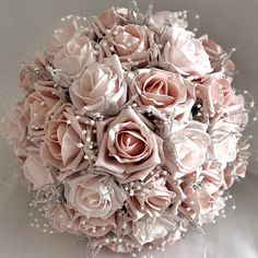 a bridal bouquet with pink roses and pearls on the bottom is sitting on a white surface