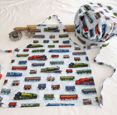 there is a apron with trains on it next to a ball of yarn and scissors