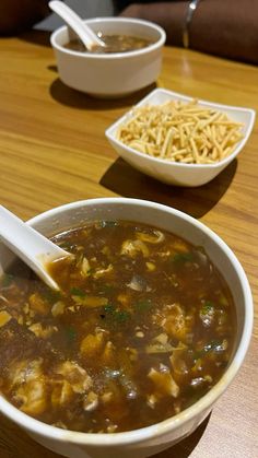 a bowl of soup is sitting on a table with two bowls of food in the background