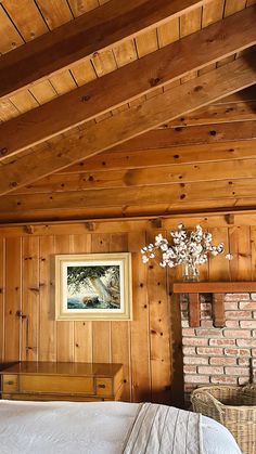 a bedroom with wood paneling and a bed in front of a brick fire place