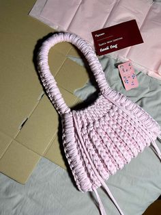 a pink handbag sitting on top of a bed next to a card and envelope