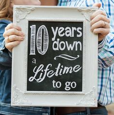 two people holding up a sign that says 10 years down and a life time to go