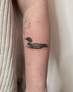 a small duck tattoo on the arm