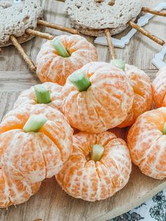 several peeled oranges sitting on top of a wooden cutting board next to pretzels